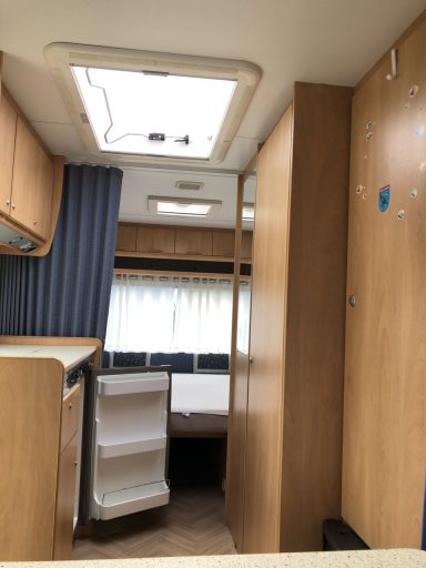 Blick zum Doppelbett im Heck. Rechts die Küche, links das Bad und gerade aus das Bett mit teilweise geschlossenem Vorhang. 